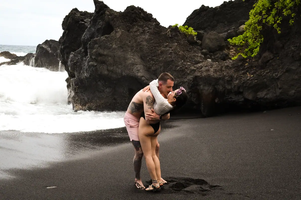 A couple standing in the surf below the sea cliffs