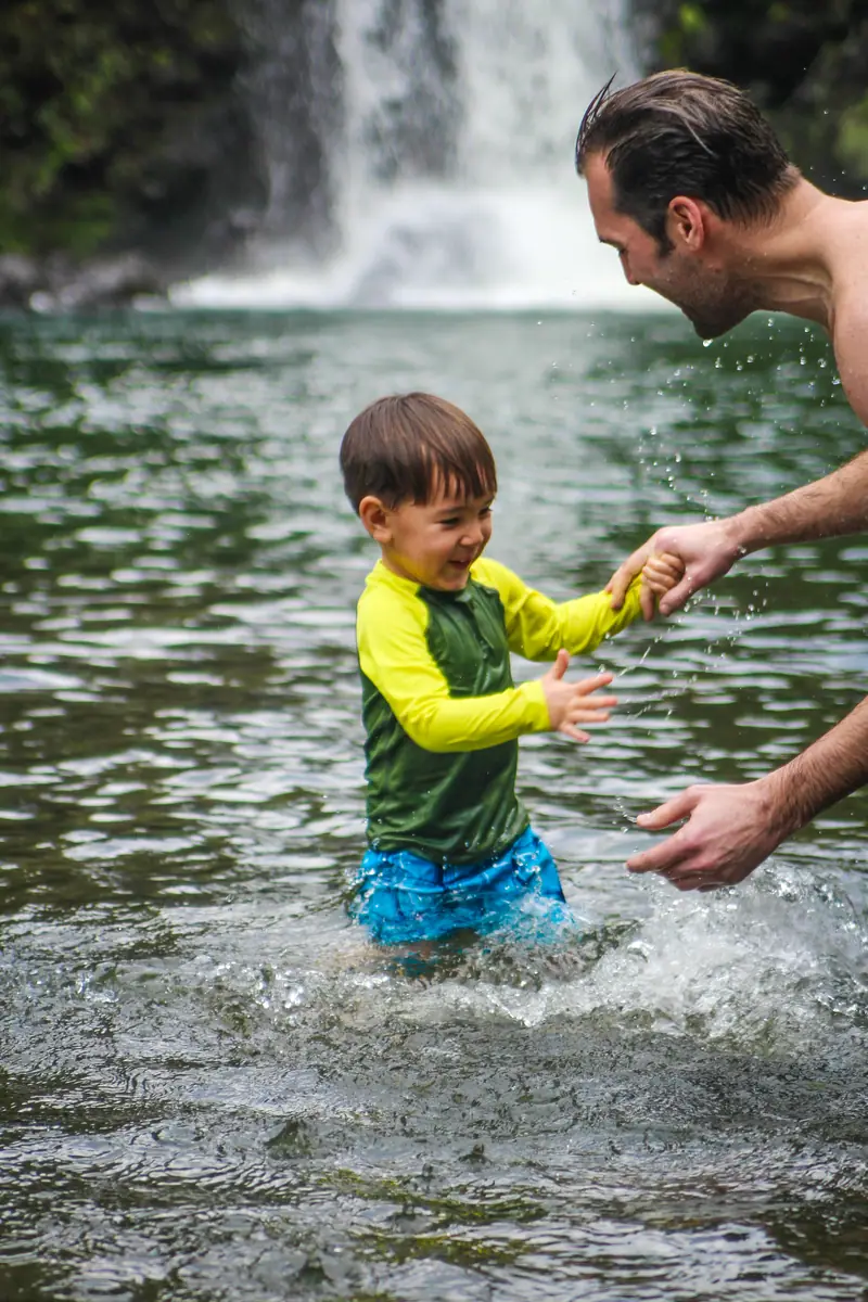 A father and his son wading into a cold freshwater pool