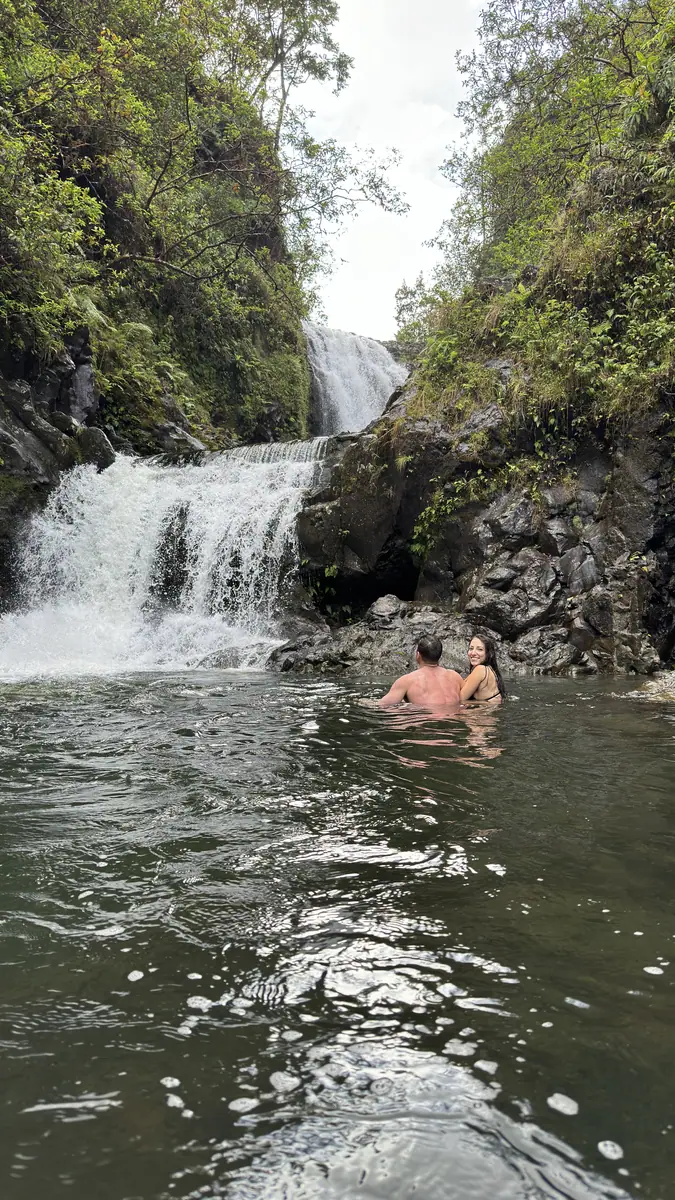 A swimmer floating under the falls