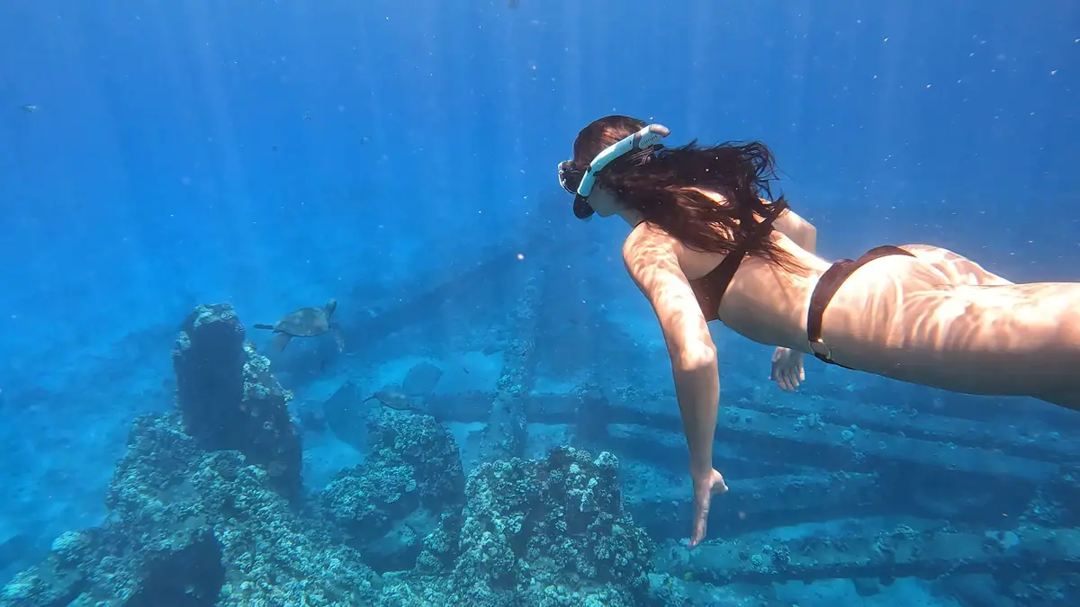 A free diver descending toward a submerged wreck