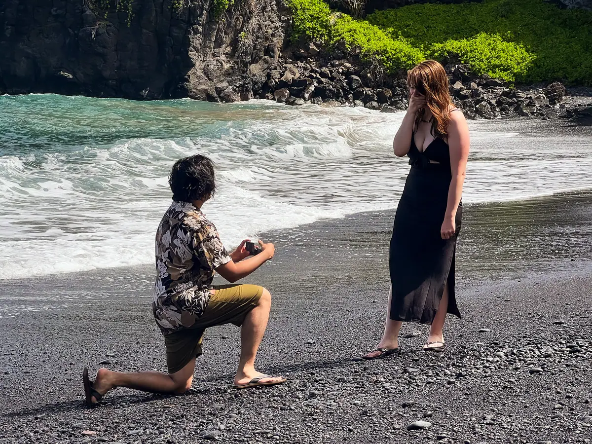 A proposal at the shoreline with the surf behind