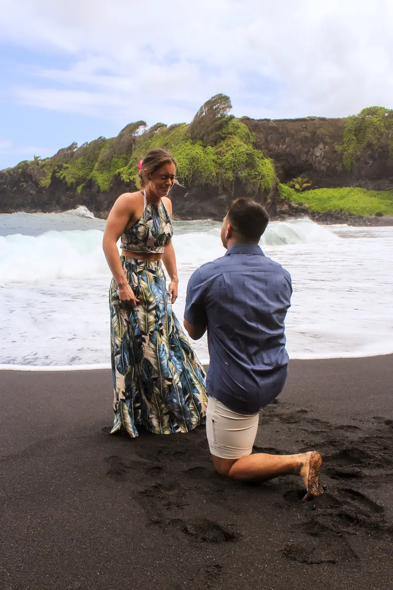 A proposal on one knee on a black sand beach